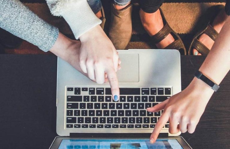 Drei Personen zeigen auf einen Laptop und optimieren eine Website.